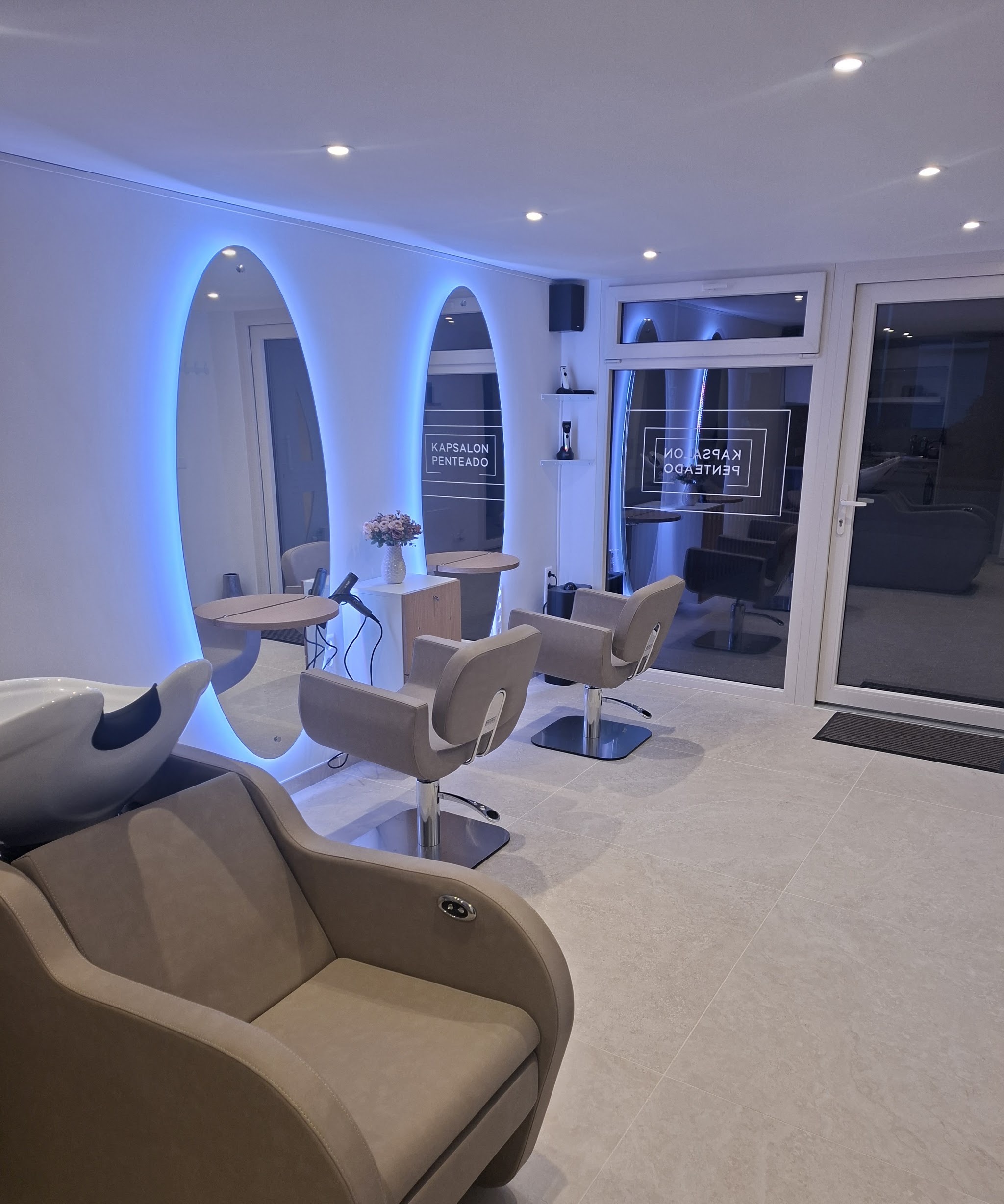 De salon: een wasstoel, twee ovale spiegels met blauw licht en de kappersstoelen